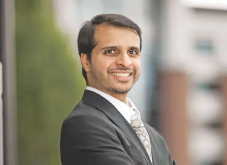 Smiling man in a suit standing by a window
